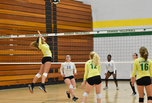 The Kennedy volleyball team spiking the ball at their game.
