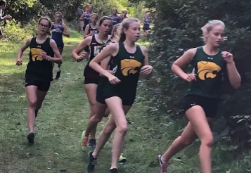 The Kennedy Girls Cross Country team racing down the winding path at their meet.