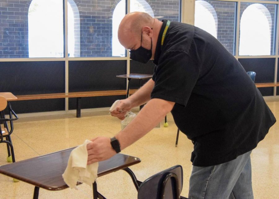 Shawn Thomsen, facilitator at Kennedy High School, disinfecting a desk to help protect students and staff.