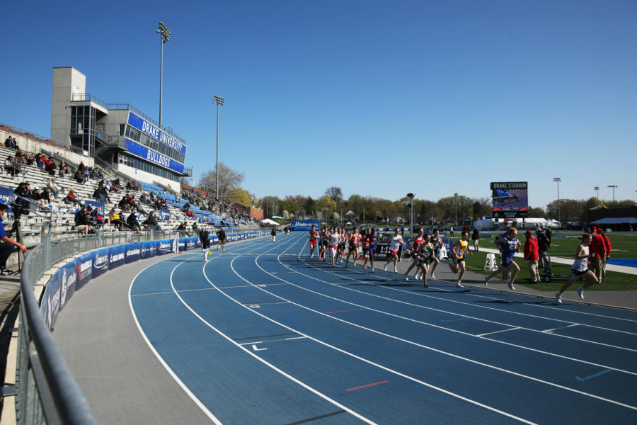 Competitors in the boys’ 3200 meter race run past partially-empty stands at Drake Stadium in Des Moines.