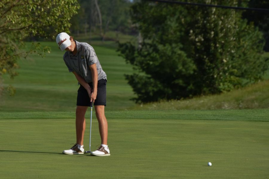 Sophomore Reid Hall putts while on a Ellis Golf Course green.