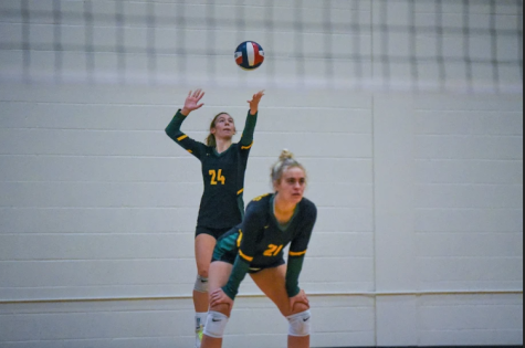 Molly Joyner serves the ball over the net at a varsity volleyball game.