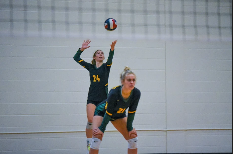Molly+Joyner+serves+the+ball+over+the+net+at+a+varsity+volleyball+game.
