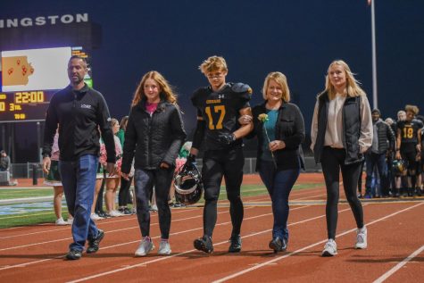 Senior Kyle Crock walks with his family during the senior night ceremony.