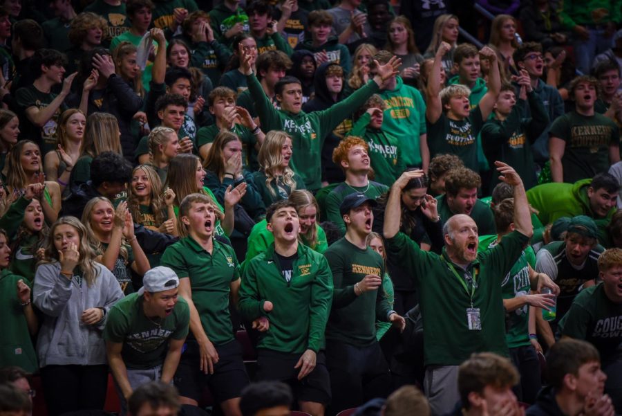 Kennedys student section turn up in a Green Out to support players, cheering over a made shot.