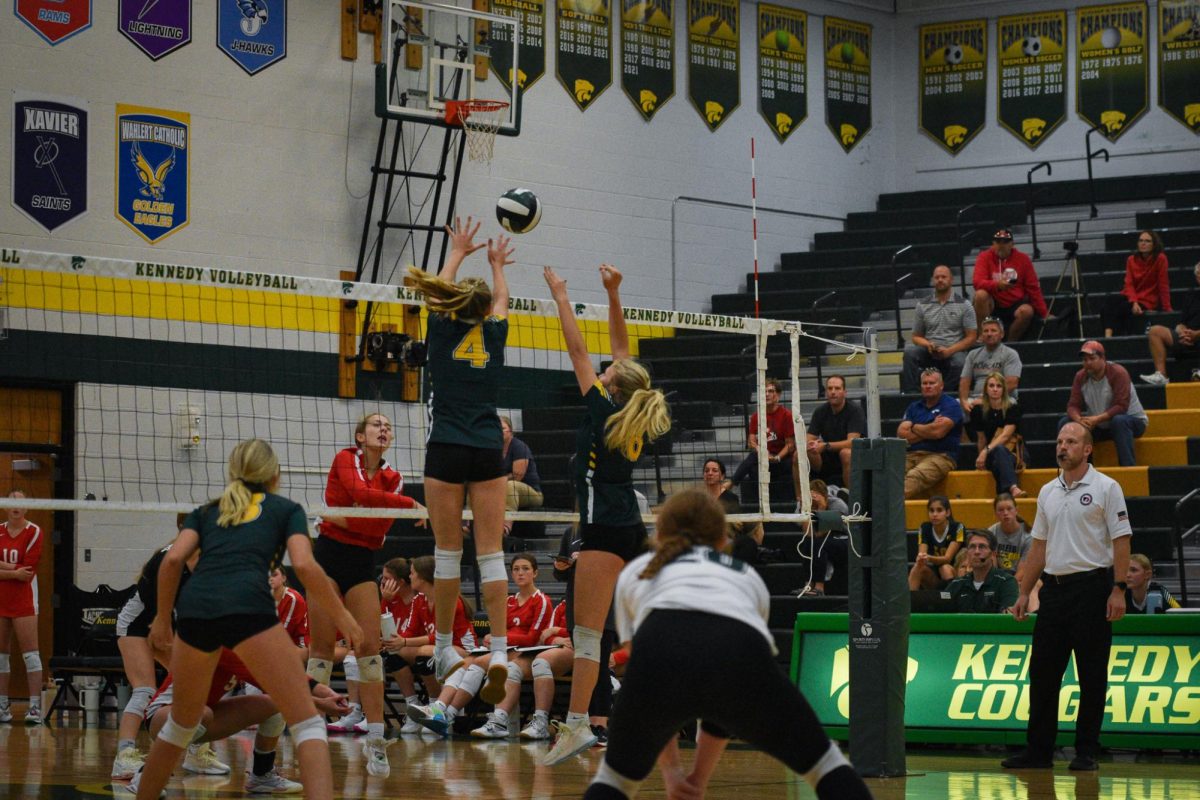 Sophomores #4 Emerson Swearinger and #8 Irelyn Ballard jump to block the ball from coming over the net.