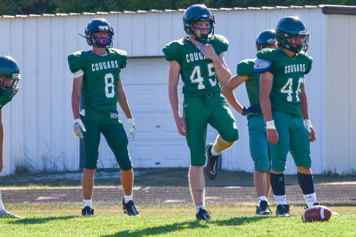 Freshmen, #45 Logan Cole, #8 Conner Ostwinkle, and #46 Griffin Mann, prepare before running a play. 