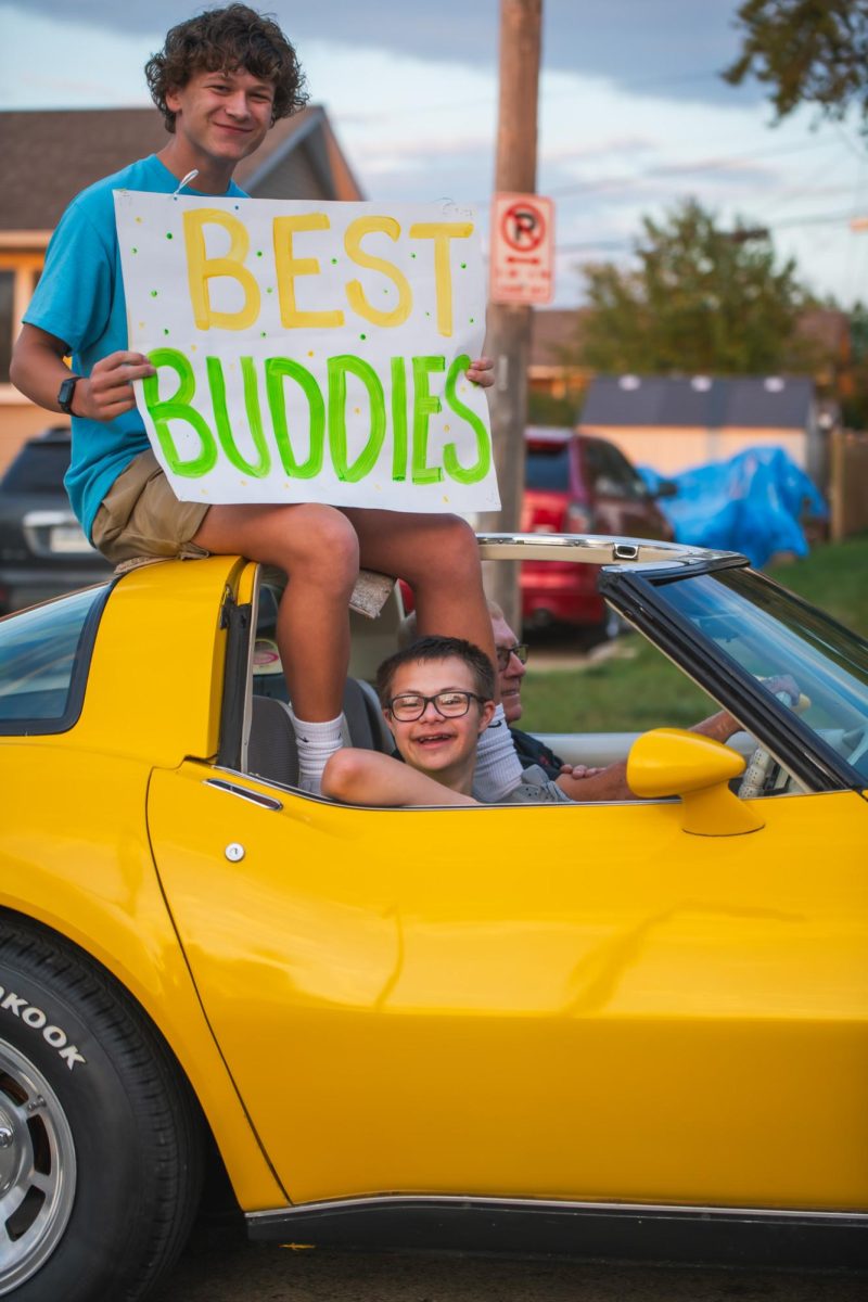 Sophomore Sam Bloomquist holds up the Best Buddies sign, accompanied by his buddy.