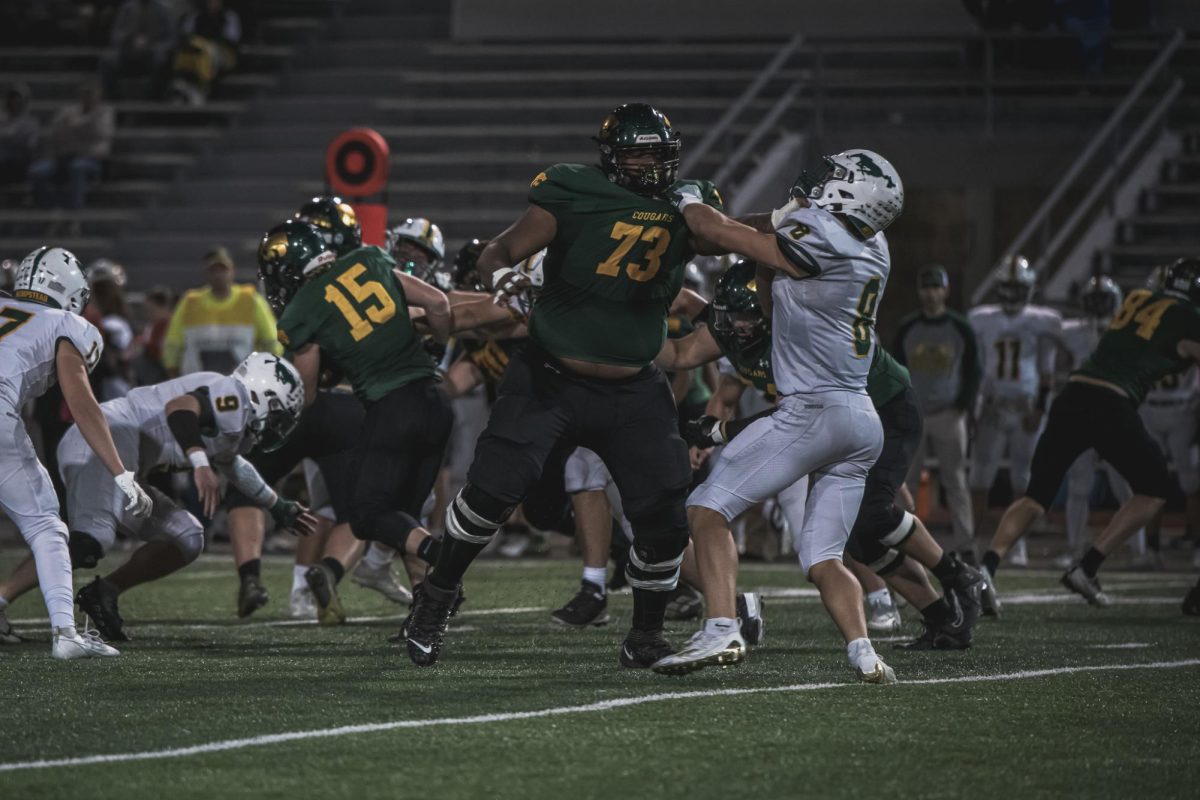 Holding off a defender, Junior Hawkeye football commit, and left tackle Nicolai Brooks helps open a gap for running back senior Trevor Scott.