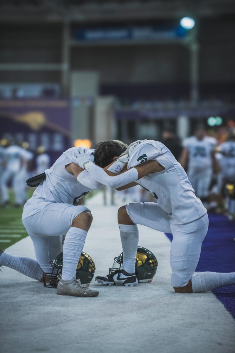 Embracing one another, seniors Christian Gasper (Left) and Nick Woods (right) join together in prayer.