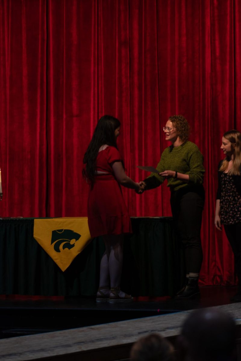 NHS inductee shakes a teachers hand and accepts the honor.