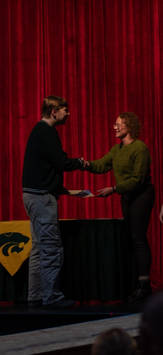 NHS inductee shakes a teachers hand and accepts the honor.