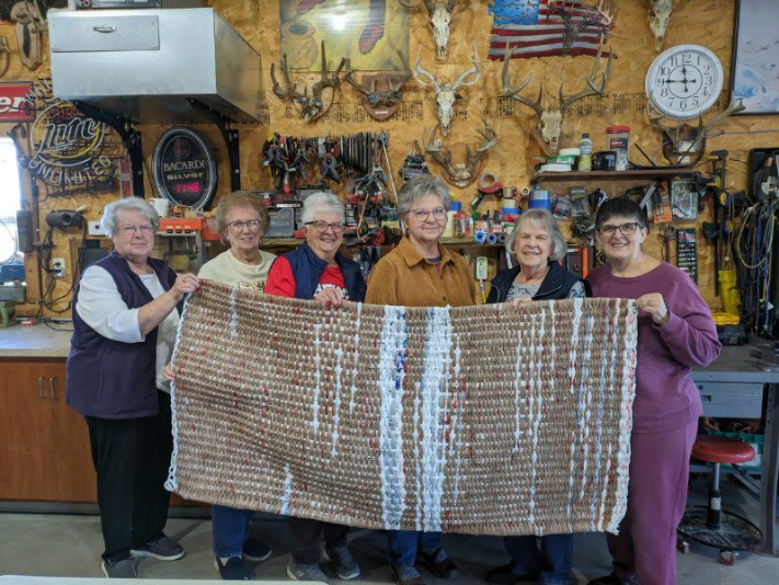 The group shows off one of the finished mats.
