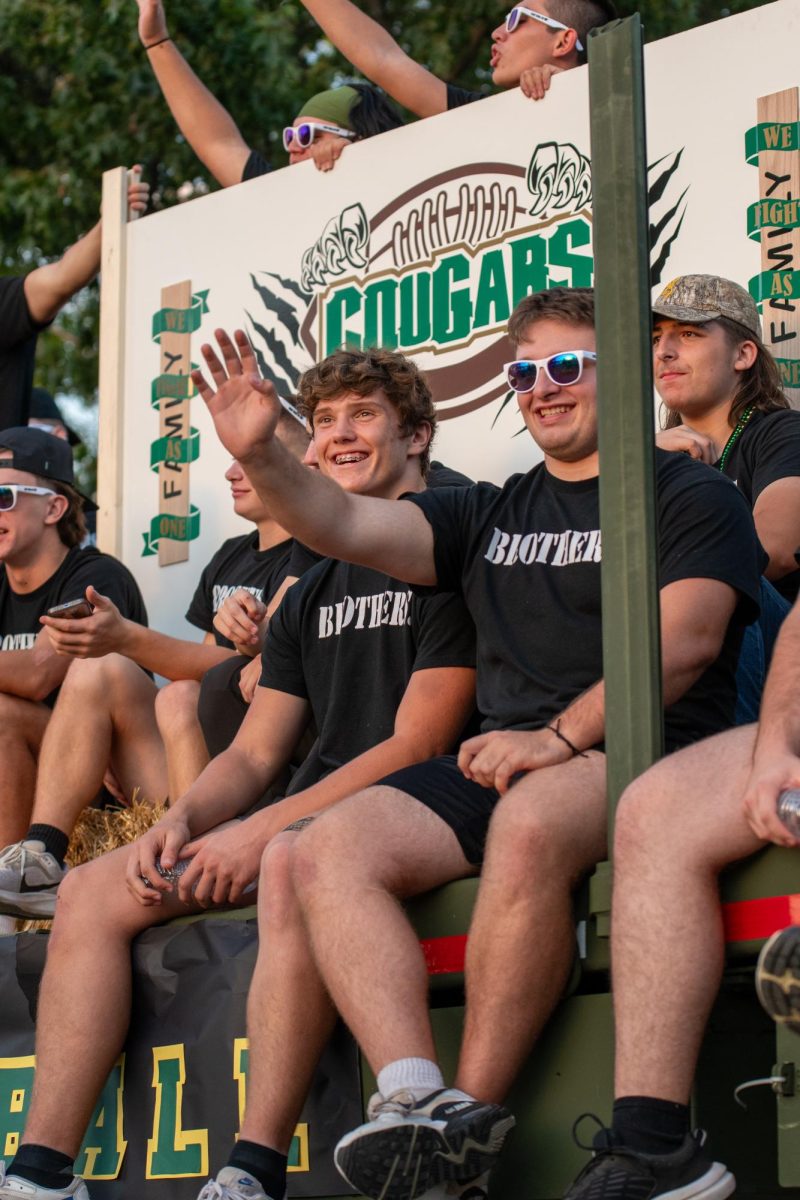 Senior Cayden Hayes and junior Henry Wilkes wave at parade onlookers.