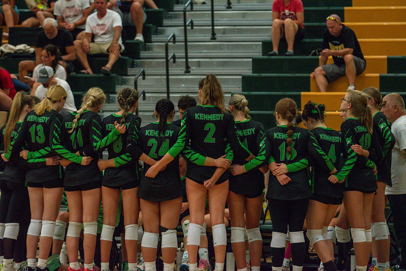 Kennedy Volleyball team huddles around bench during time out. 