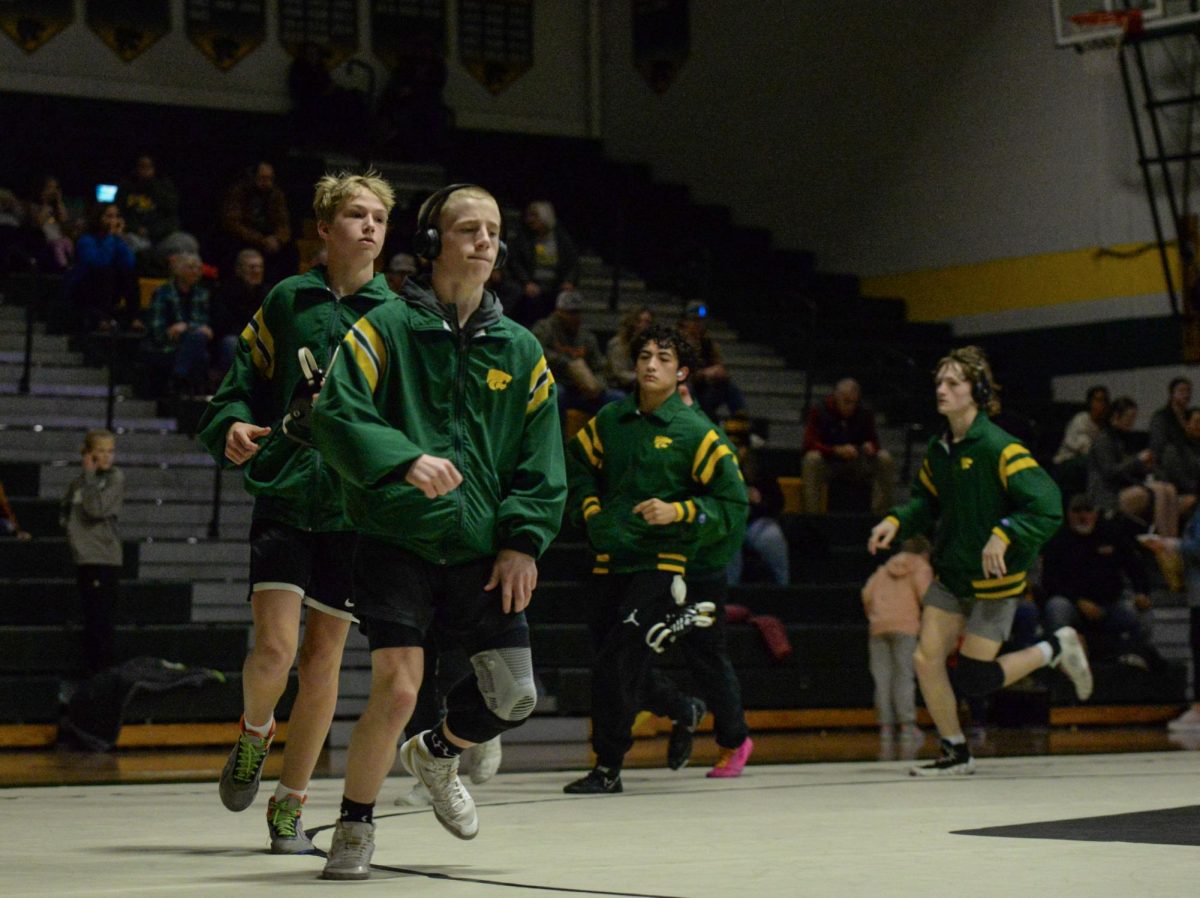 Varsity boys wrestlers run onto the mat to open the Varsity meet.