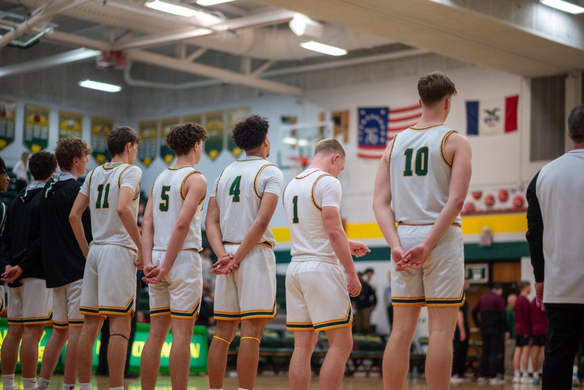 During the national anthem,  the Kennedy basketball team stands together.