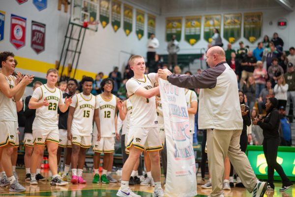 Senior Trey McKowen receives the Boys Basketball State Qualifier banner from Kennedy athletic director Shawn Thomsen.