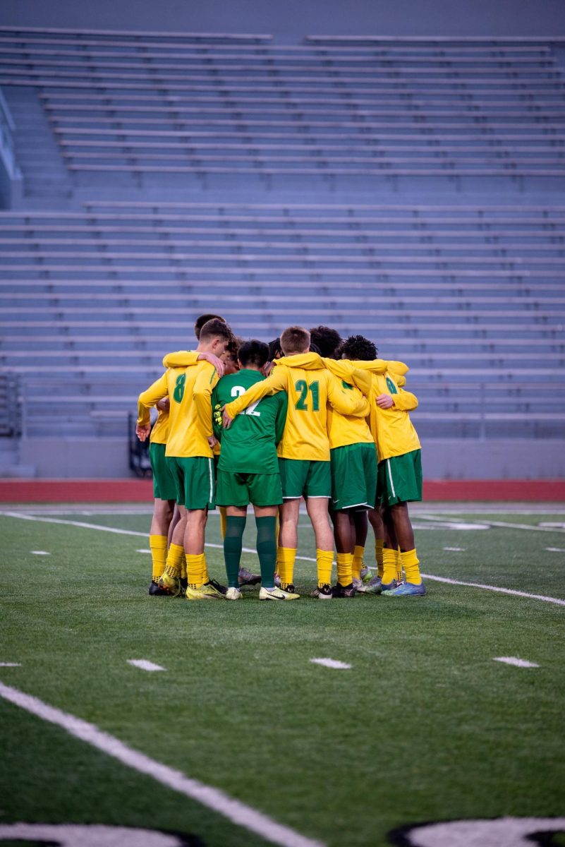 Before the match, the Kennedy varsity boys soccer team stands in a huddle. 
