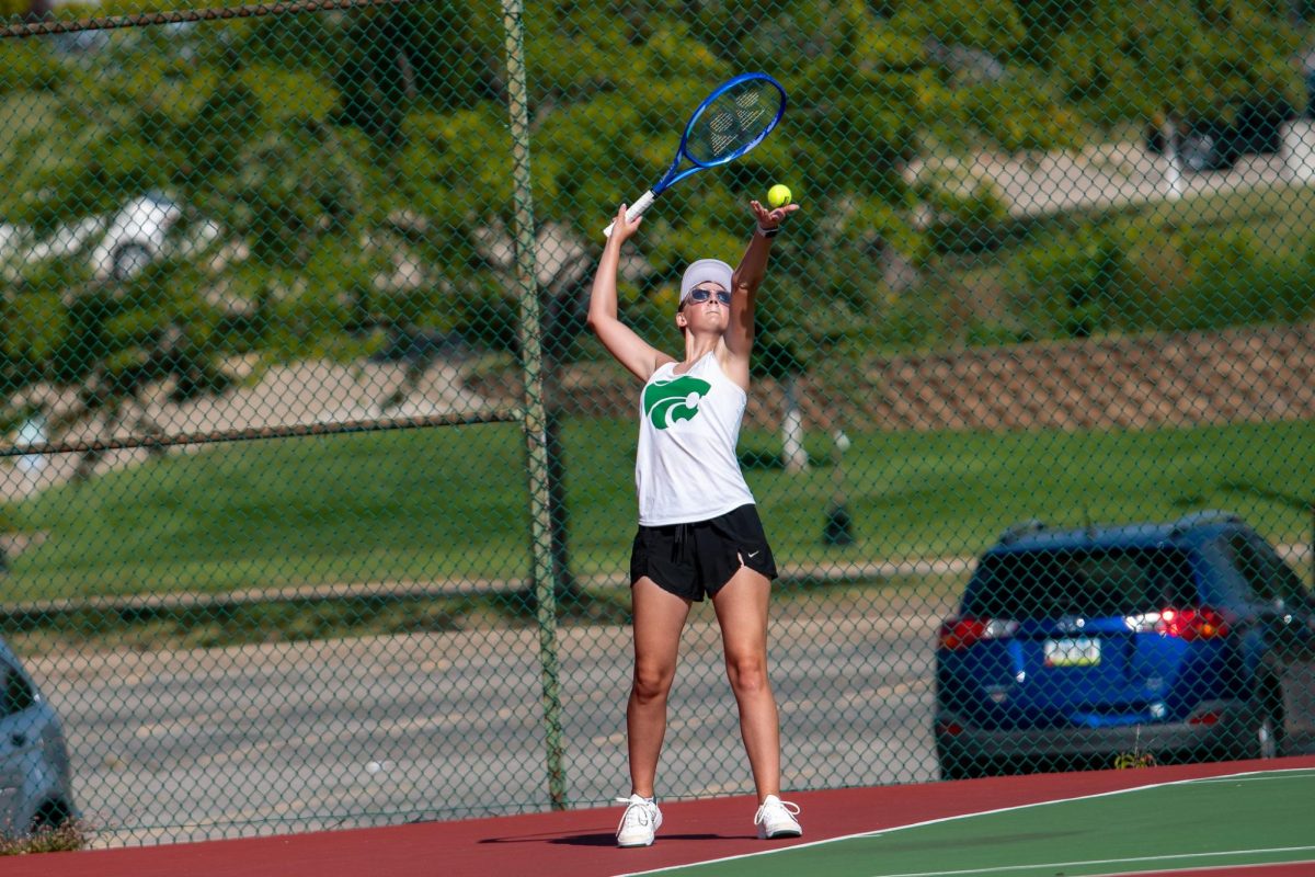 Preparing the serve, Junior Katie Hubbs throws the ball in the air ready to hit the ball.