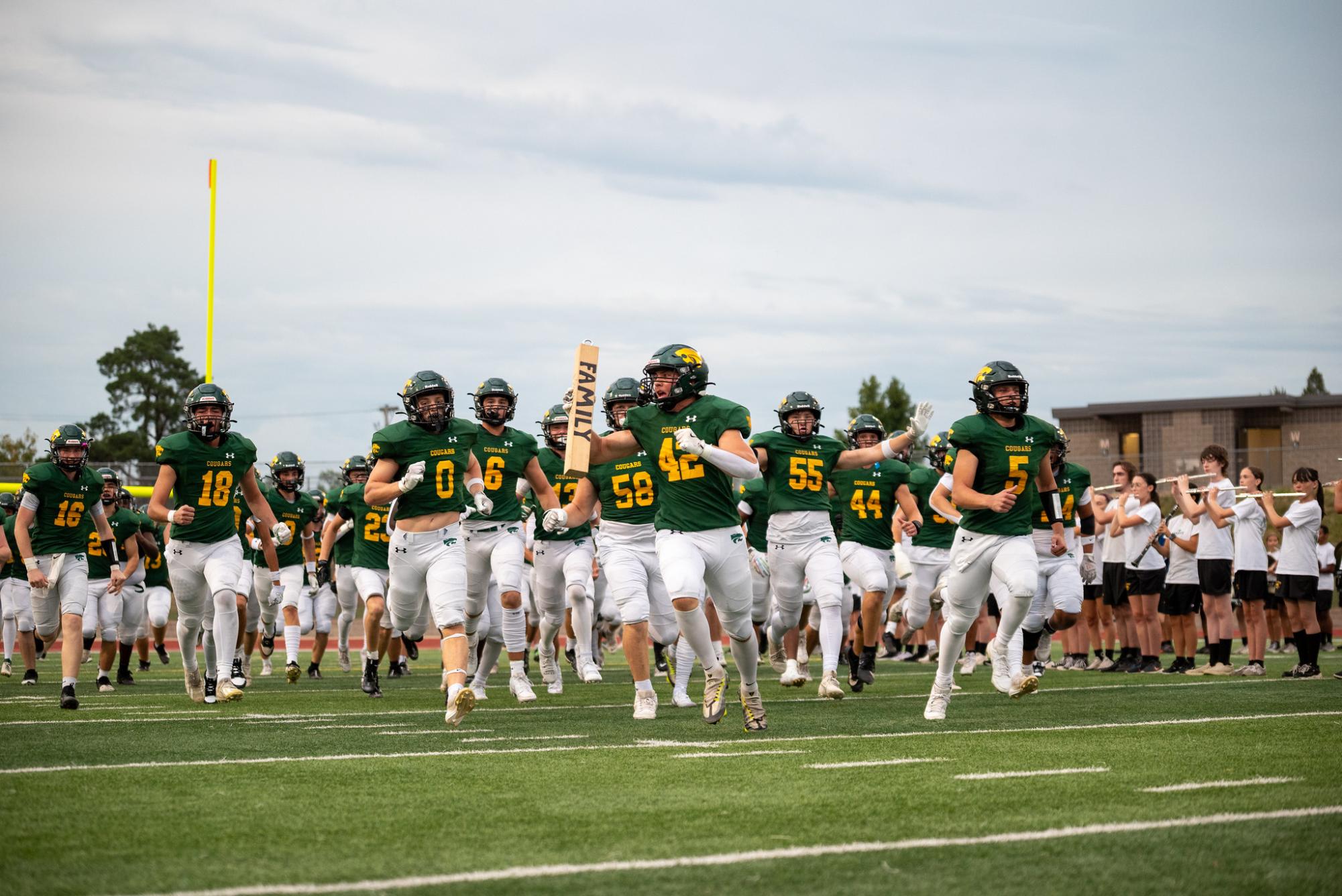 Leading the team out of the tunnel, junior Jarron Weber carries the "Family Stick".