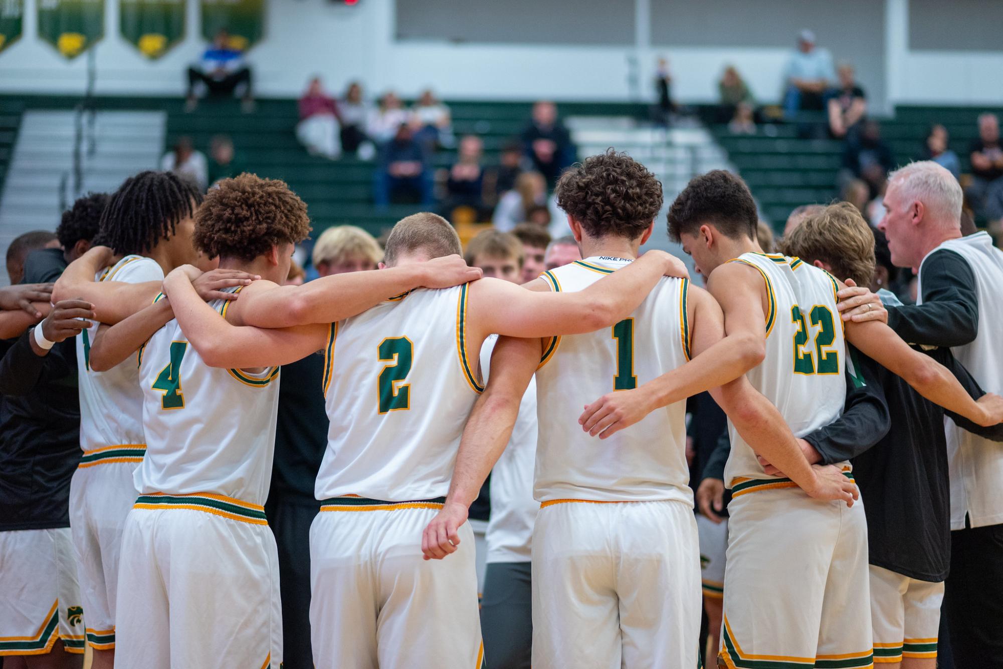 Before first tipoff, the Kennedy Varsity Boys Basketball team stands in a huddle.