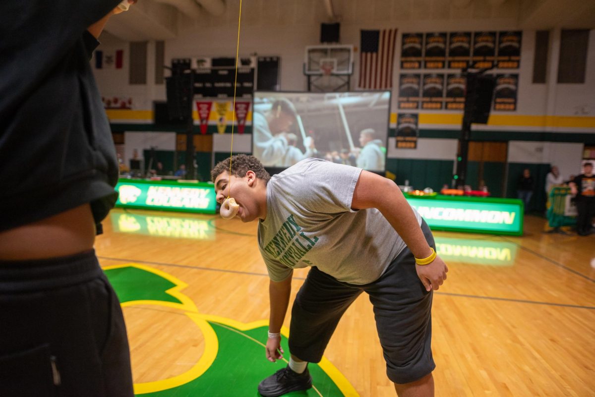 Participating in the donut on a stick challenge, junior King Johnson holds the stick up for junior Karter Alberts.