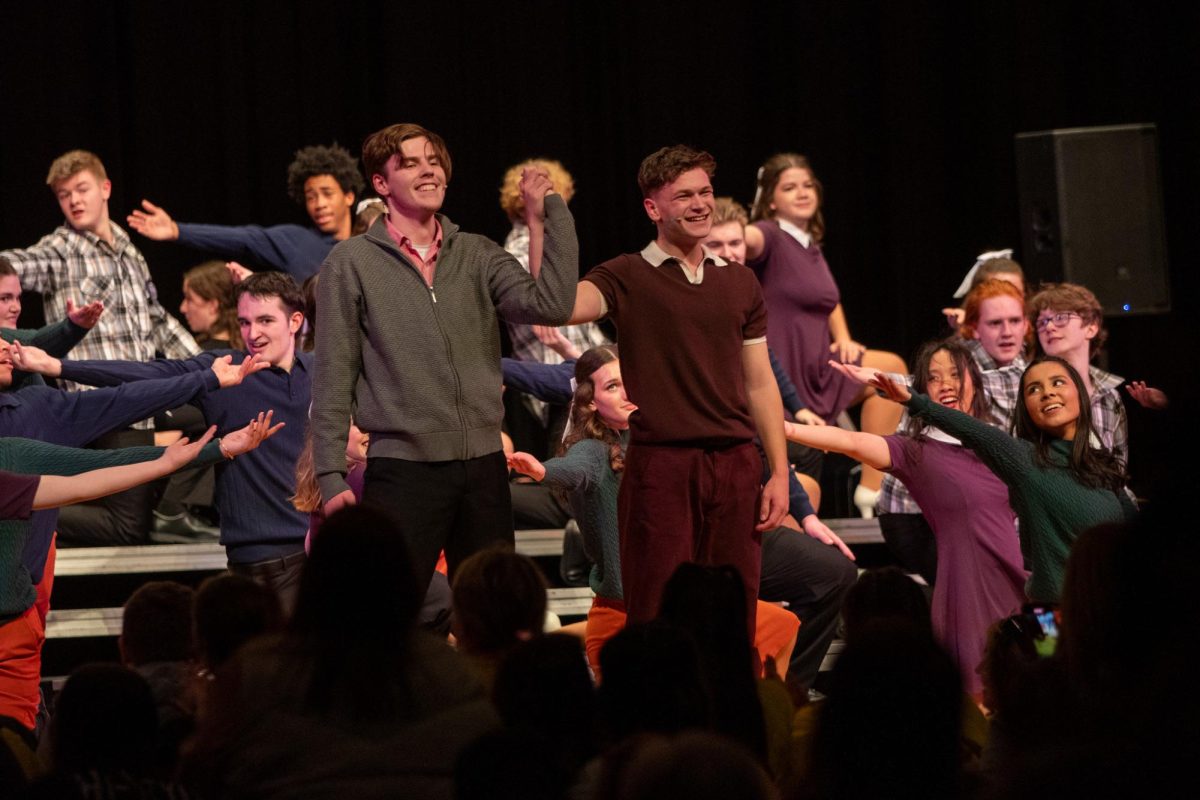 Jordan Harvey '25 and Sam Bloomquist '26 raise their hands as they come together in the 24-25 Happiness show. 