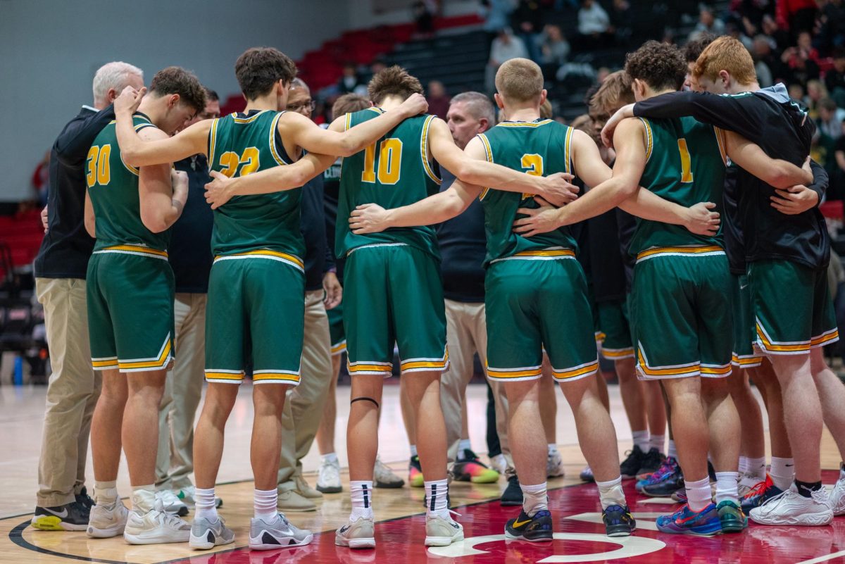Standing together before the game, the Kennedy Varsity Boys basketball team talks it over with the coaches.